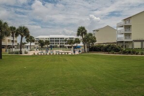 A resort with a pool area, palm trees, and a large building with multiple balconies. - Sea Cliffs rental with elevator SUN-SUN Rental (Port Saint Joe)