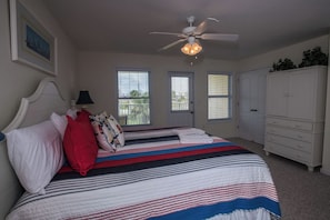 A bedroom with a bed, a ceiling fan, a dresser, and a door with windows. - Sea Cliffs rental with elevator SUN-SUN Rental (Port Saint Joe)