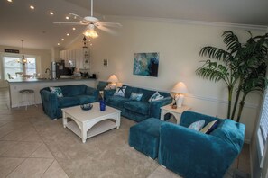 A living room with teal sofas, a white coffee table, and a kitchen in the background. - Sea Cliffs rental with elevator SUN-SUN Rental (Port Saint Joe)