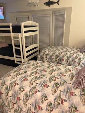 A bedroom with bunk beds, a patterned bedspread, a television, and a ceiling fan. - Sea Cliffs rental with elevator SUN-SUN Rental (Port Saint Joe)