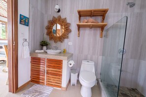 Ein modernes Badezimmer mit Waschtisch aus Holz, einer Glasdusche und einem Spiegel mit ungewöhnlichem Rahmen.