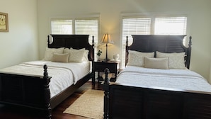 A bedroom with two wooden beds, white bedding, a nightstand with a lamp, and a small potted plant. - Spectacular Ocean Front Home In Beautiful Islamorada!Slip,Com Pool, & Prv Bch (Islamorada)