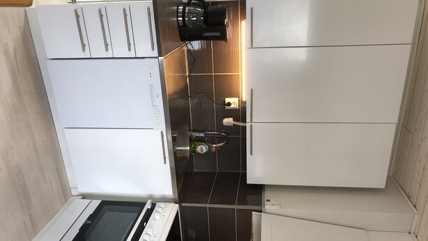 A compact kitchen with a built-in oven, a coffee maker, and a small sink.