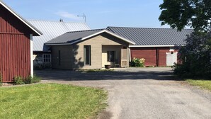 A two-story building with a gravel driveway leading to a wooden door.
