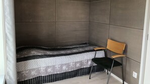 A small, enclosed room with a bed, a chair, and a curtain.