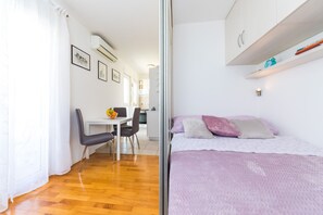 Quarto compacto com cama, escrivaninha pequena e cadeira.