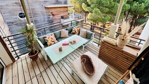 A wooden deck with a sofa, table, and potted plants. - Apartment Benvenuti Calvi the beach with feet with 3 min, terrace, carpark, swimming pool (Calvi)