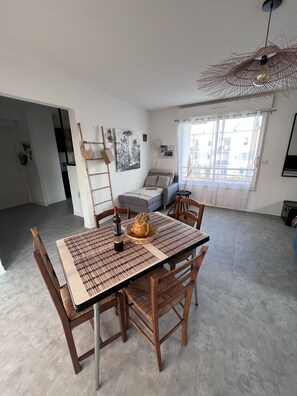 En rummelig opholdsstue med spisebord, stole, sofa og et stort vindue med udsigt.