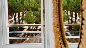 A room with a window overlooking a dense green tree area. - Apartment Benvenuti Calvi the beach with feet with 3 min, terrace, carpark, swimming pool (Calvi)