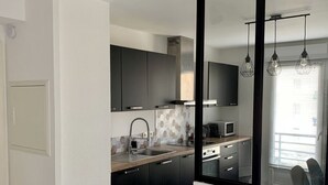 A modern kitchen with black cabinets, a stainless steel range hood, and a microwave. - Apartment Benvenuti Calvi the beach with feet with 3 min, terrace, carpark, swimming pool (Calvi)