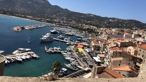 A marina with boats docked, surrounded by buildings and mountains. - Apartment Benvenuti Calvi the beach with feet with 3 min, terrace, carpark, swimming pool (Calvi)