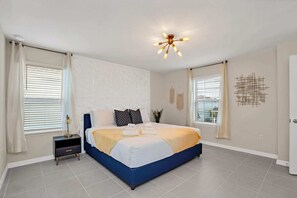 Ein Schlafzimmer mit Bett, Nachttisch, Vorhängen, einer Deckenleuchte und einer Wanddekoration.