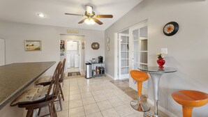 A kitchen with a dining area, a ceiling fan, and a clock on the wall.