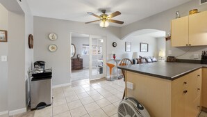A kitchen with a ceiling fan, a dishwasher, and a refrigerator. There is a dining area with a table and chairs.