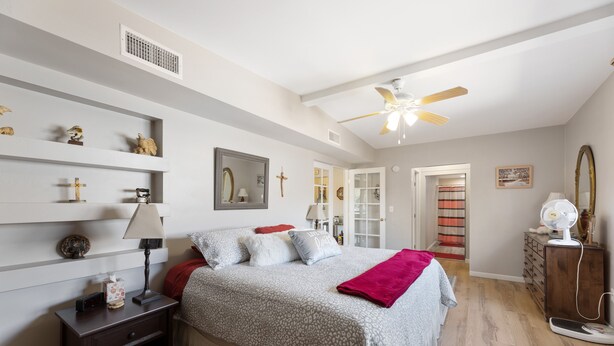 A bedroom with a bed, nightstand, dresser, and a ceiling fan.