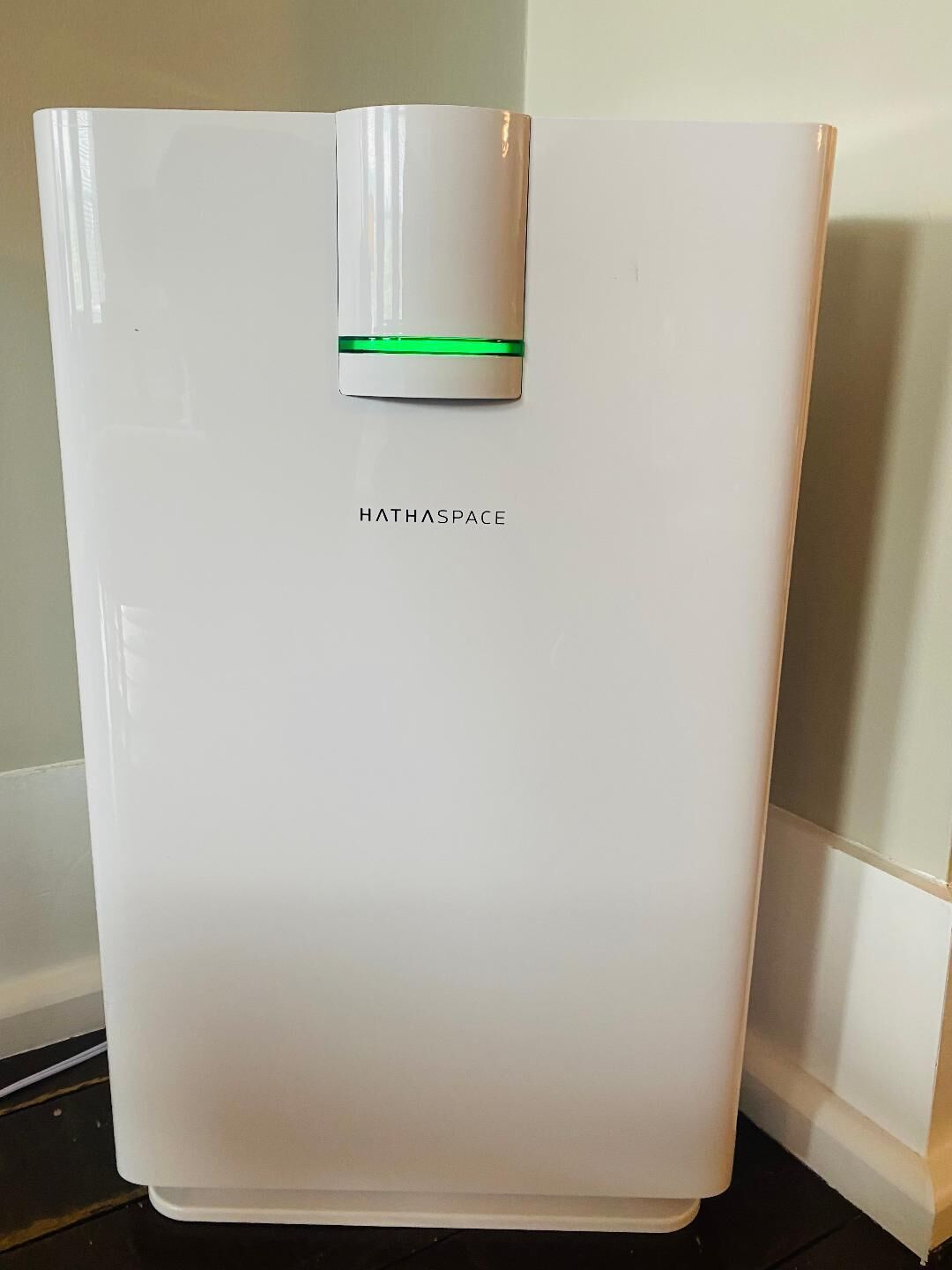 Ein weißer, moderner Kühlschrank mit grüner Leuchte und dem Schriftzug "HATHASPACE" vorne.