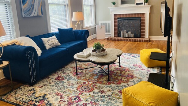 A living room with a blue sofa, a yellow armchair, a fireplace, and a large mirror.