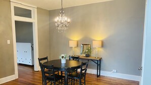 A dining area with a round table, black chairs, a chandelier, and wall-mounted lamps.