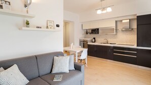 A modern kitchen with white cabinets, a black refrigerator, and a dining area with a white table and chairs. - Ossuccio Island View - MyHomeInComo (Tremezzina)