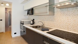 A modern kitchen with a built-in microwave, stainless steel sink, and a glass backsplash. - Ossuccio Island View - MyHomeInComo (Tremezzina)