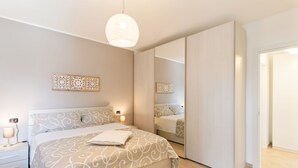A modern bedroom with a large bed, bedside lamps, a mirror, and a wardrobe. - Ossuccio Island View - MyHomeInComo (Tremezzina)