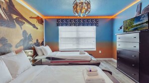 A hotel room with a bed, a dresser, a window with blinds, a wall mural, and a ceiling light fixture. - Disney Getaway w/ Private Pool & Spa (Kissimmee)