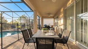 A covered patio with a pool, outdoor furniture, and a view of the backyard. - Disney Getaway w/ Private Pool & Spa (Kissimmee)