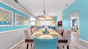 A dining room with a long table, blue chairs, and a chandelier. - Disney Getaway w/ Private Pool & Spa (Kissimmee)