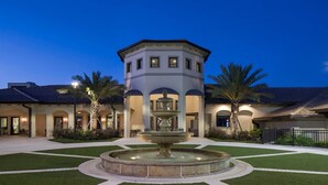 A courtyard with a central fountain, palm trees, and a building with arched doorways. - 8BR Villa w/ Private Pool | Theater |Themed BRs (Davenport)
