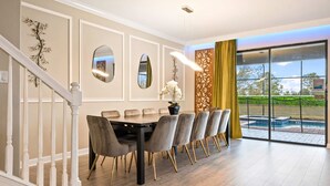 A dining area with a long table and chairs, a staircase, and a view of a swimming pool. - 8BR Villa w/ Private Pool | Theater |Themed BRs (Davenport)