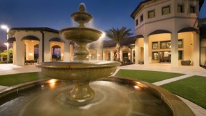 A fountain in a courtyard with a building featuring arched walkways and outdoor seating. - 8BR Villa w/ Private Pool | Theater |Themed BRs (Davenport)