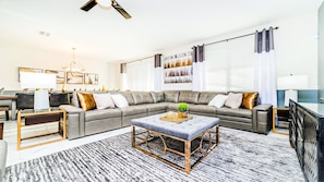 A modern living room with a sectional sofa, a coffee table, and a dining area with a glass table.