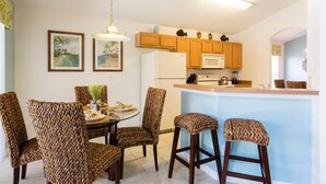 A compact kitchen with wooden cabinets, a white refrigerator, and a bar area.