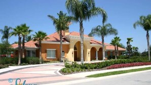 A resort building with a red-tiled roof, arched entrance, and palm trees.