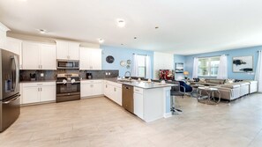 Una cocina moderna con armarios blancos, electrodomésticos de acero inoxidable y una isla central.