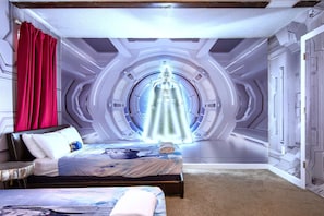 A bedroom with a circular ceiling design, a bed with a blue and white patterned bedspread, and a red curtain.