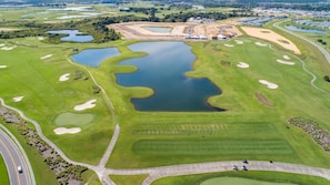 An aerial view of a golf course with multiple ponds, sand bunkers, and a road.