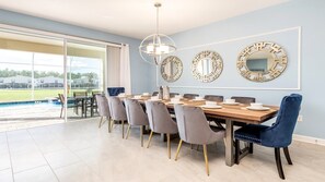 A dining area with a wooden table, grey upholstered chairs, and three wall-mounted mirrors. - Star Wars Suite & Epic Spider-Man Game Room (Kissimmee)