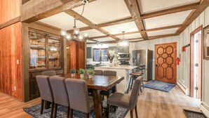 Una cocina amplia con vigas de madera, un comedor con una mesa grande y sillas, y una isla de cocina moderna.