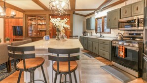 Una cocina moderna con una isla central, taburetes de bar, electrodomésticos de acero inoxidable y vigas de madera.