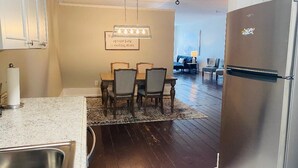A modern kitchen with a dining area, stainless steel appliances, and a view into the living room. - Amazing 1 Bedroom Apartment, Downtown Jonesborough (Jonesborough)