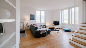 A modern living room with a sofa, a TV, and a staircase. - MyHomeInComo - Modern Luxury Attic (Como)