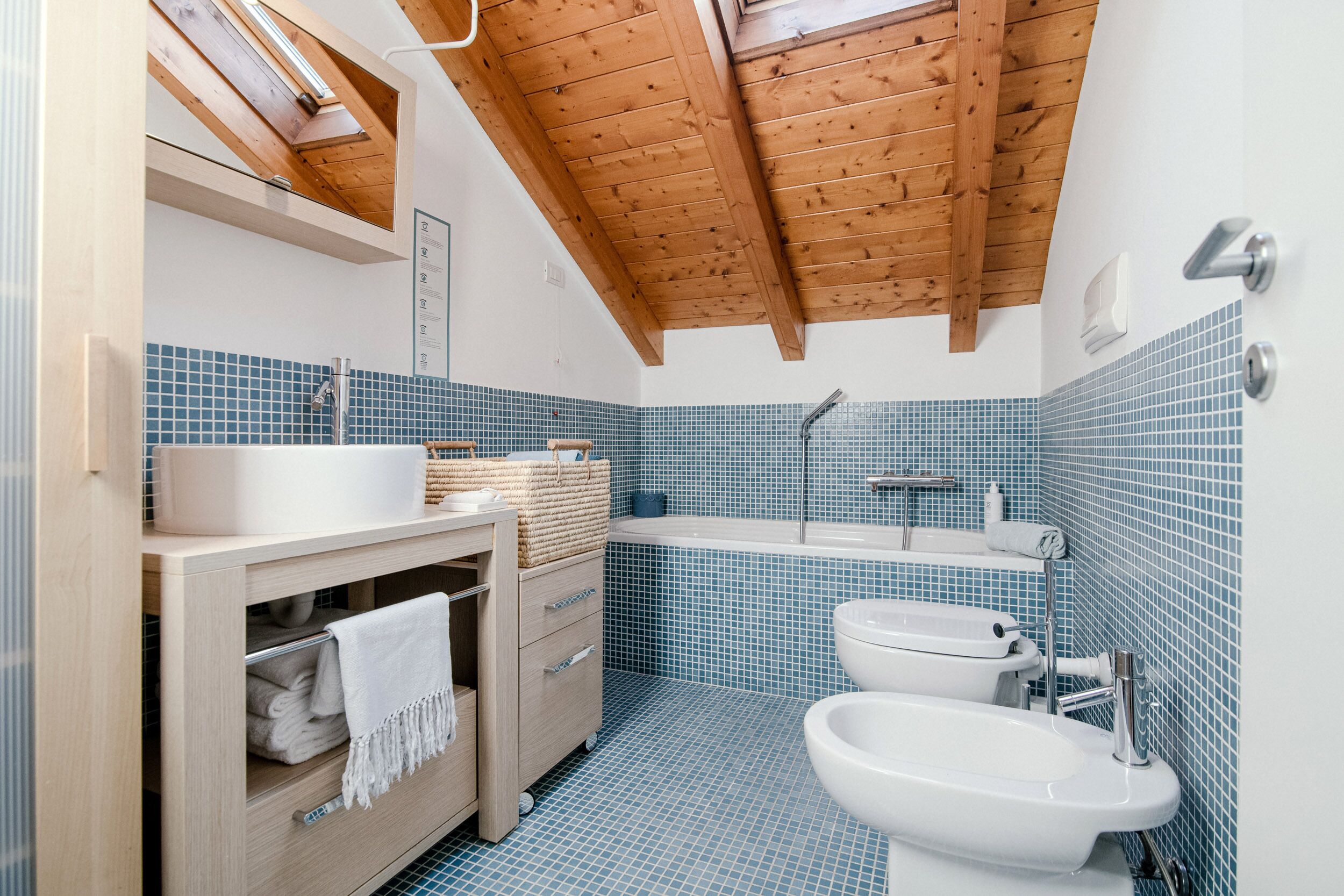 Un baño con techo de madera, un lavabo, un bidé y un espejo.