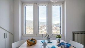 A dining area with a table set for two, a wooden crate, a candelabra, and a book on the table. - MyHomeInComo - Modern Luxury Attic (Como)