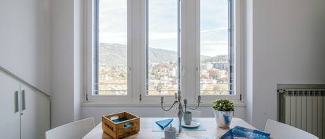 Un comedor con una mesa dispuesta para dos personas, un cesto de madera, un candelabro y un libro sobre la mesa.