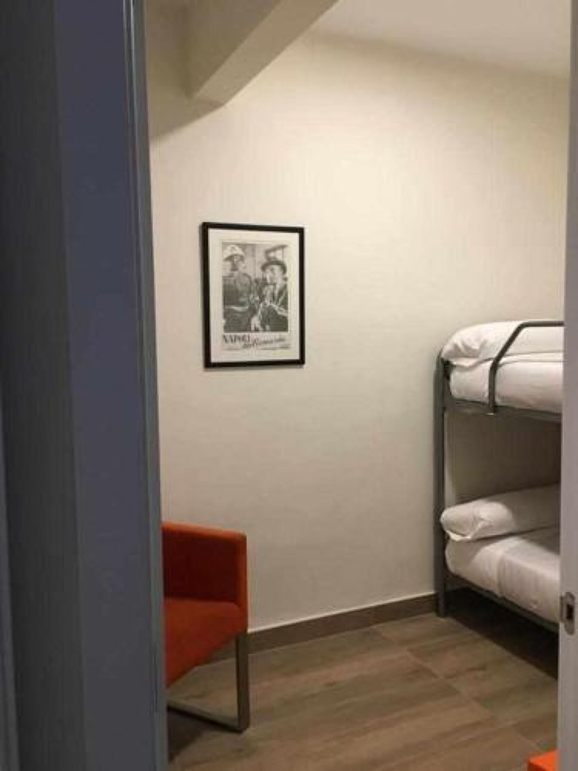 Una habitación con literas, un cuadro en la pared y una sola silla.