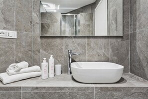 Un bagno moderno con una vasca freestanding, uno specchio sopra il lavabo e un portaservizi con asciugamani piegati.