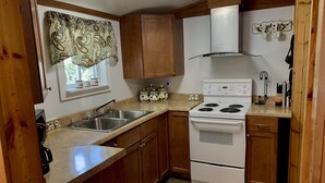 Une cuisine de taille réduite, avec des meubles en bois, une cuisinière blanche et un évier en acier inoxydable.