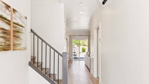 A modern hallway with a staircase, a dining area, and a view of the outdoors.