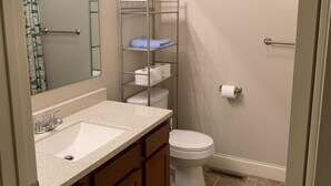 Un baño con lavamanos, espejo, inodoro y estantes.